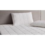 Close-up image of a bed with a quilted mattress protector and pillow protector