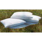 Photo of three pillows stack on top of one another. They're sitting on top of a mirrored podium in a grass field.