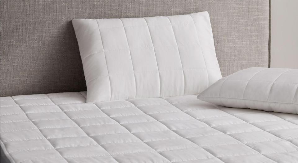Close-up image of a bed with a quilted mattress protector and pillow protector
