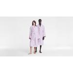 A man and woman stand side by side in front of a blank white set. Both are modelling Aven Stripe bathrobes in lilac.
