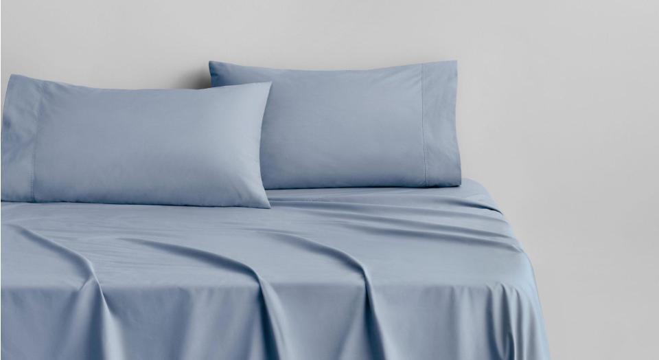 A bed dressed in Byren Percale sheets in the colour blue mist.