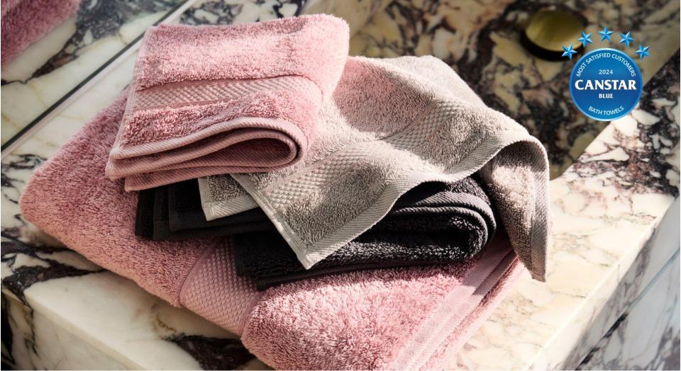 sheridan bath towels in pink and cream draped over white marble counter