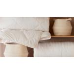 what do you need for a comfortable bed. close up shot of woven baskets and quilts stacked on wooden shelving.
