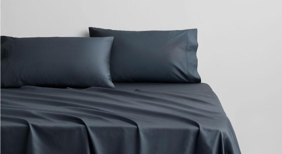 A bed dressed in Egyptian Cotton Sateen sheets in the shade nocturnal, a dark navy blue.
