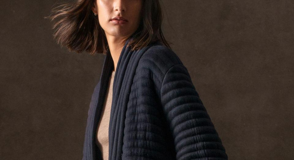 A cropped image of a young woman with short brown hair, wearing a navy Sheridan bathrobe.