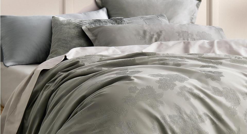 guest bedroom ideas, close up of smoke green quilt cover and pillowcases, with grey sheets. cream wall in background.