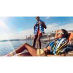 A young man and woman lounging by the beach with Sheridan beach towels draped over their shoulders