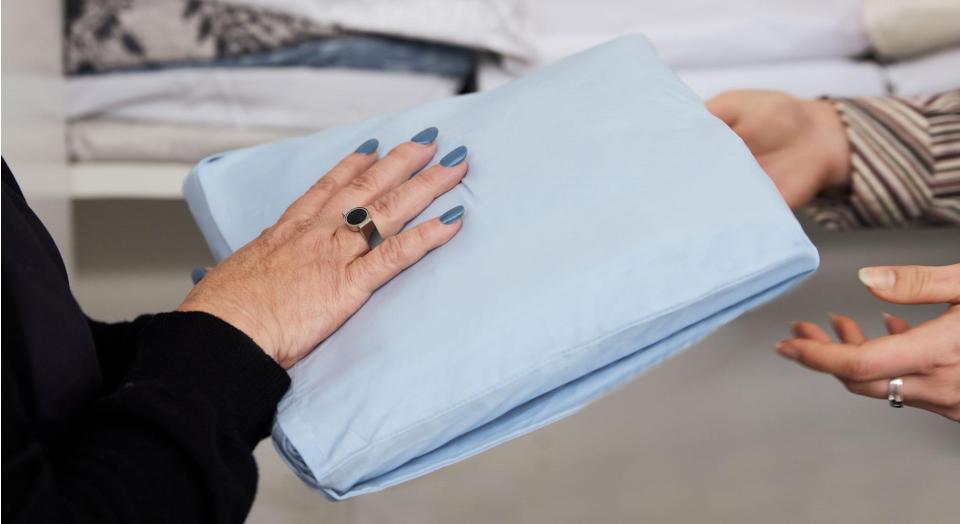A close-up of two pairs of hands passing a SleepSafe sleep kit between them