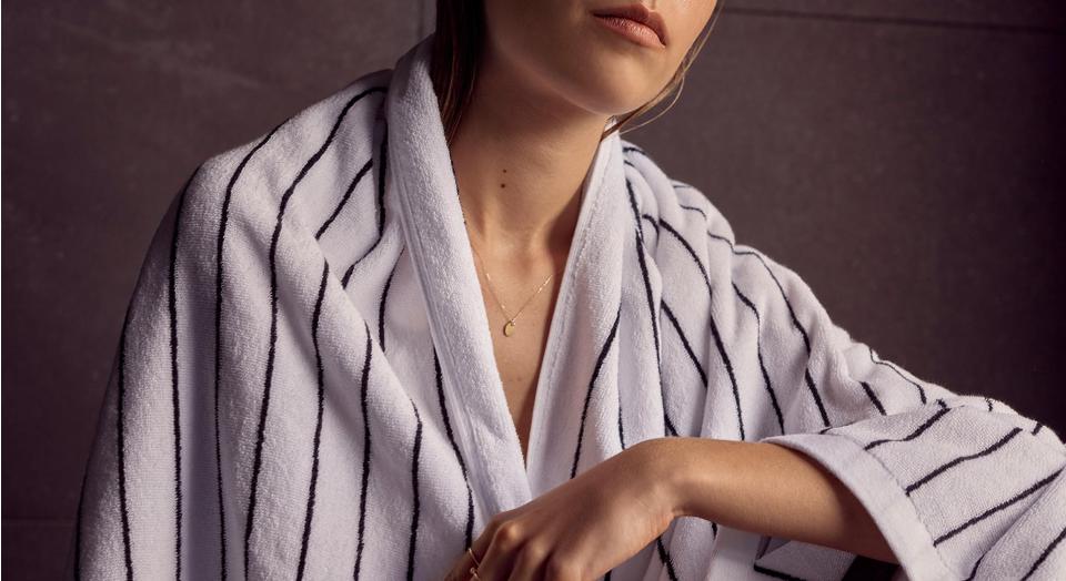white woman wear white and navy striped towel around her shoulders