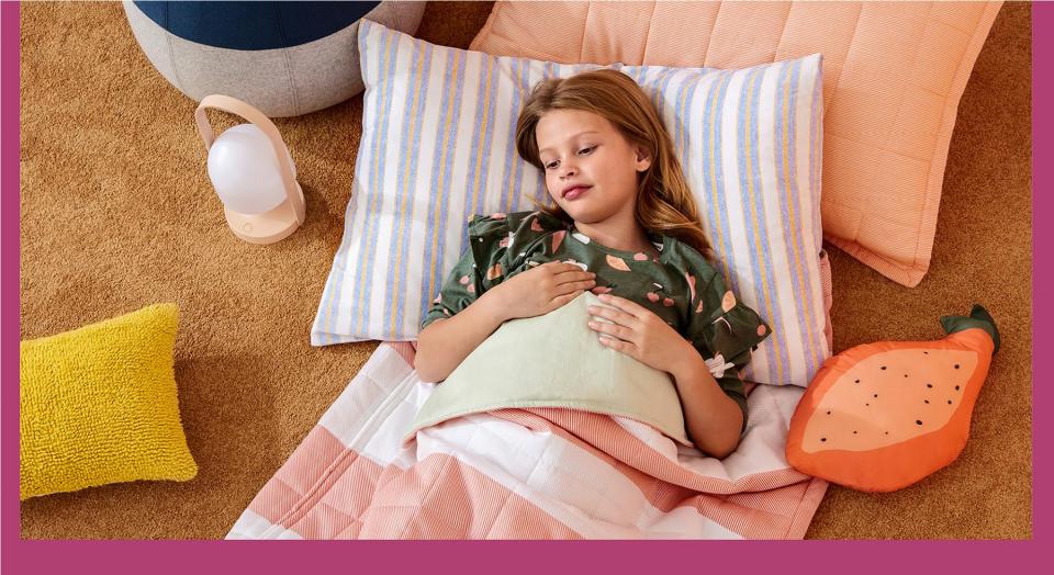 pre-teen girl in sleepover quilt sleeping bag on floor with cushions