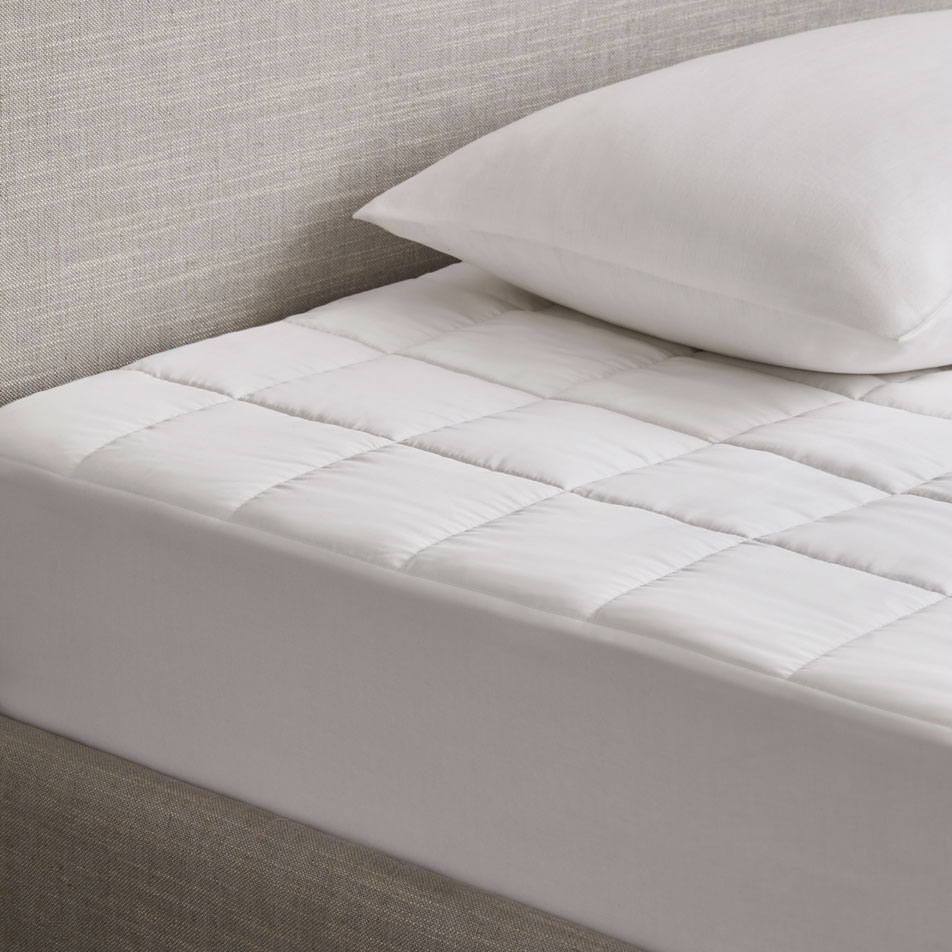 Close-up of an unmade bed with a mattress protector and pillow on top