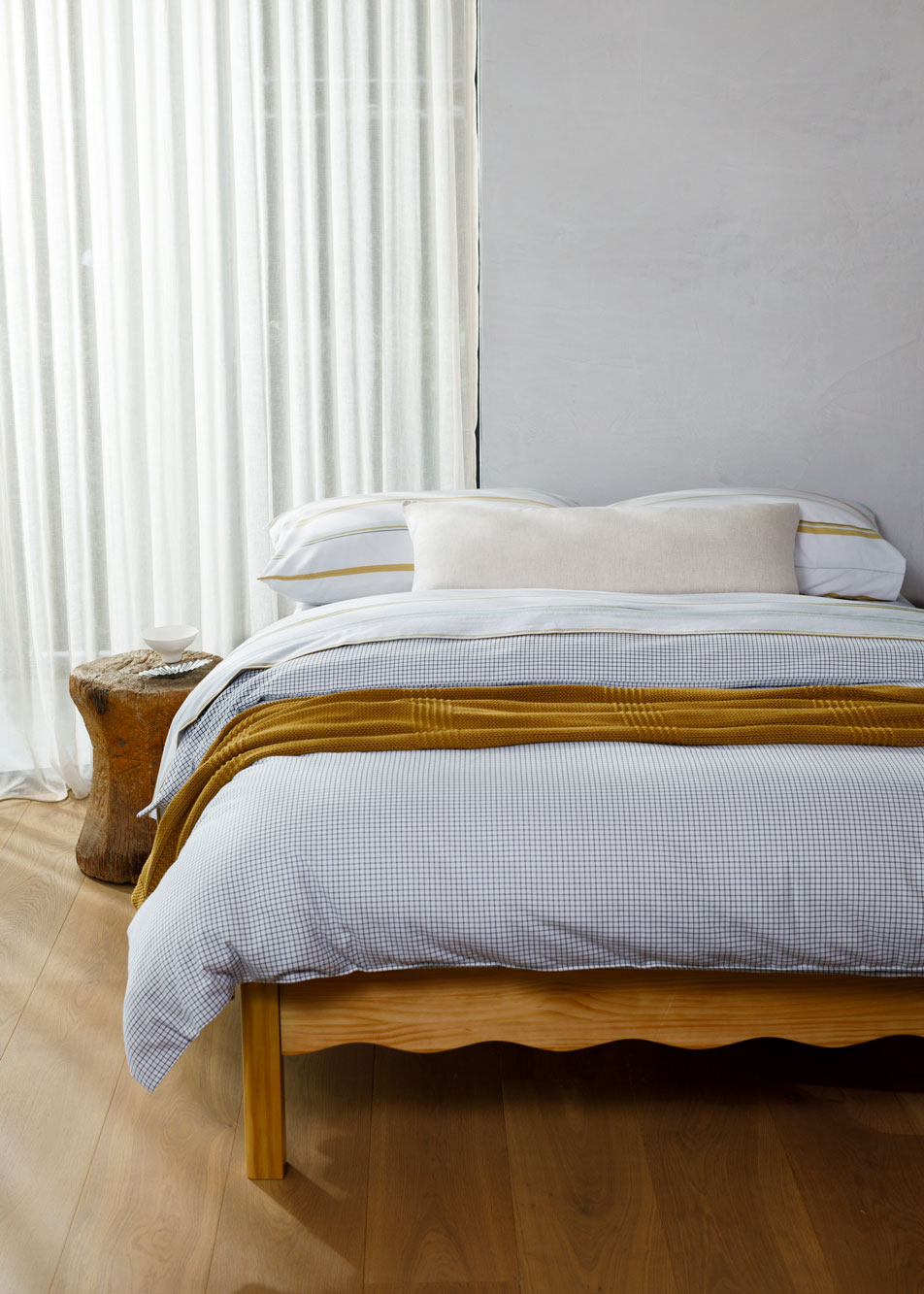 A bed made up with white check and striped flannelette bedding