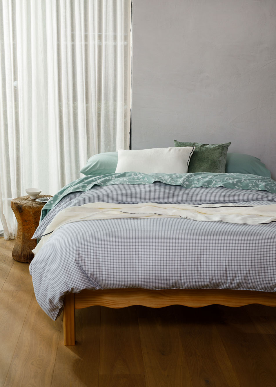 A bed made up with checkered and floral flannelette sheets