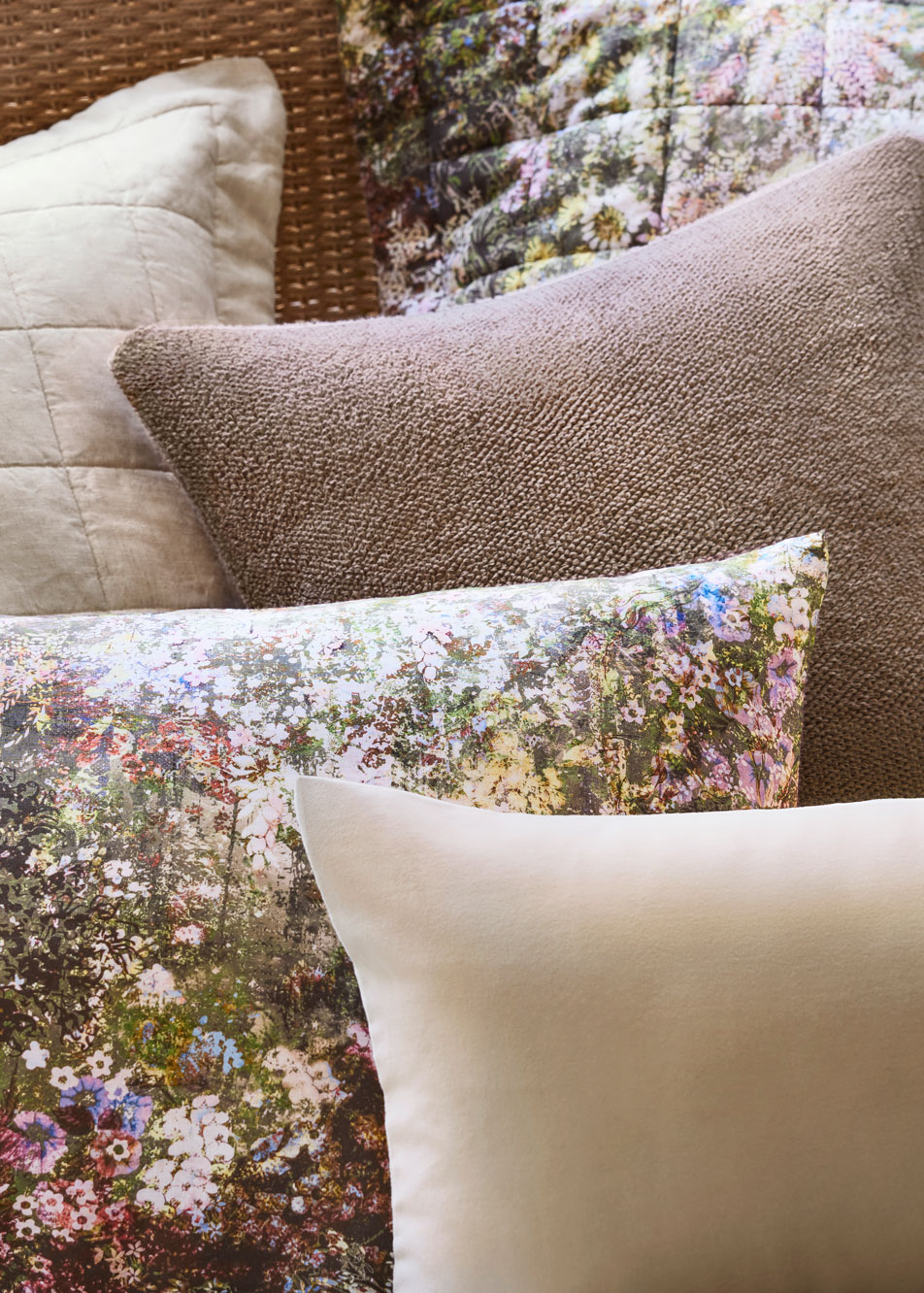 A close-up of layers of cushions styled on a bed