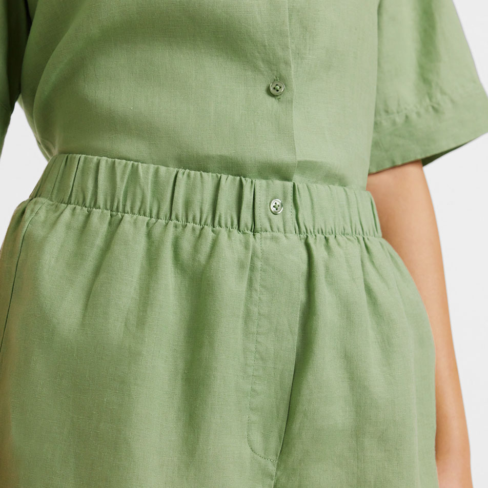 A close up of a model wearing green Abbotson Linen shorts.