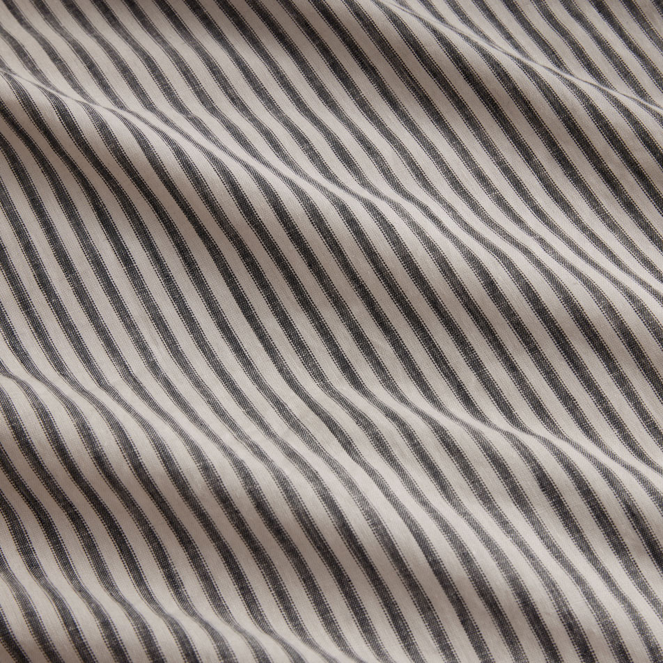 Close up photo of an Abbotson Linen Ticking Stripe sheet set in carbon. A matching pillow sits on top.