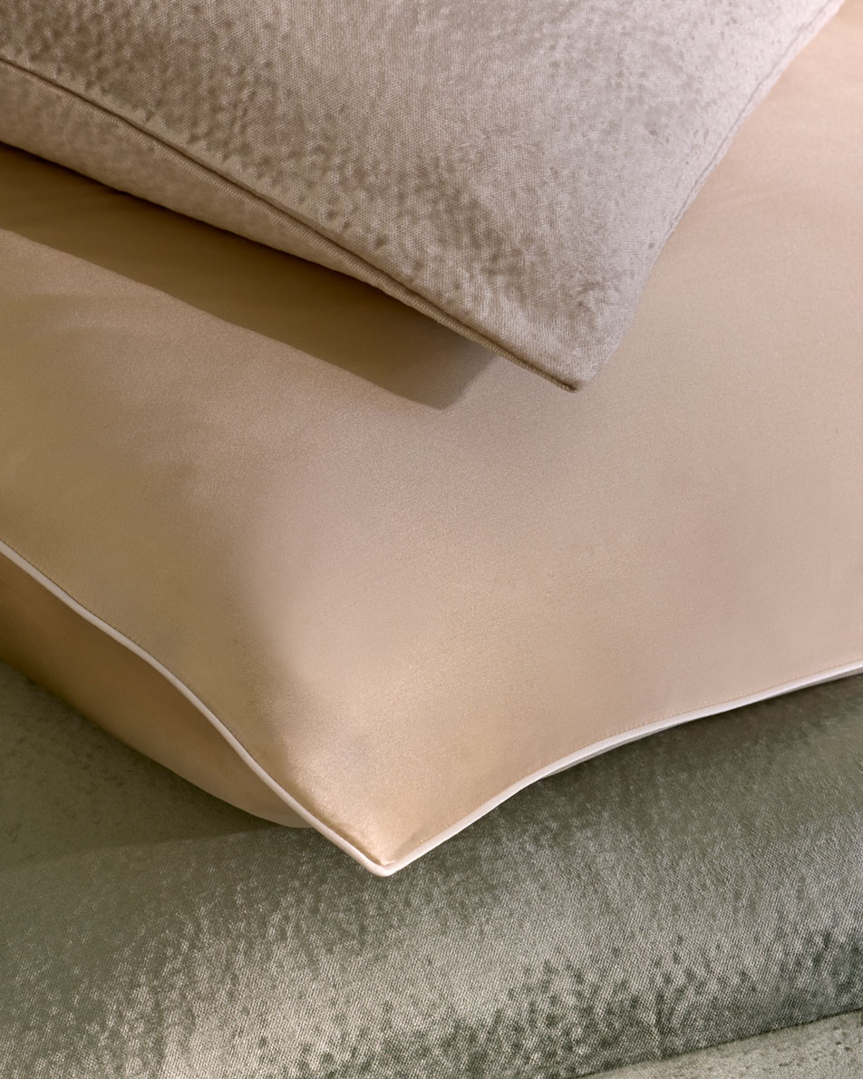 A close-up of three different cushions in three neutral and green colours.