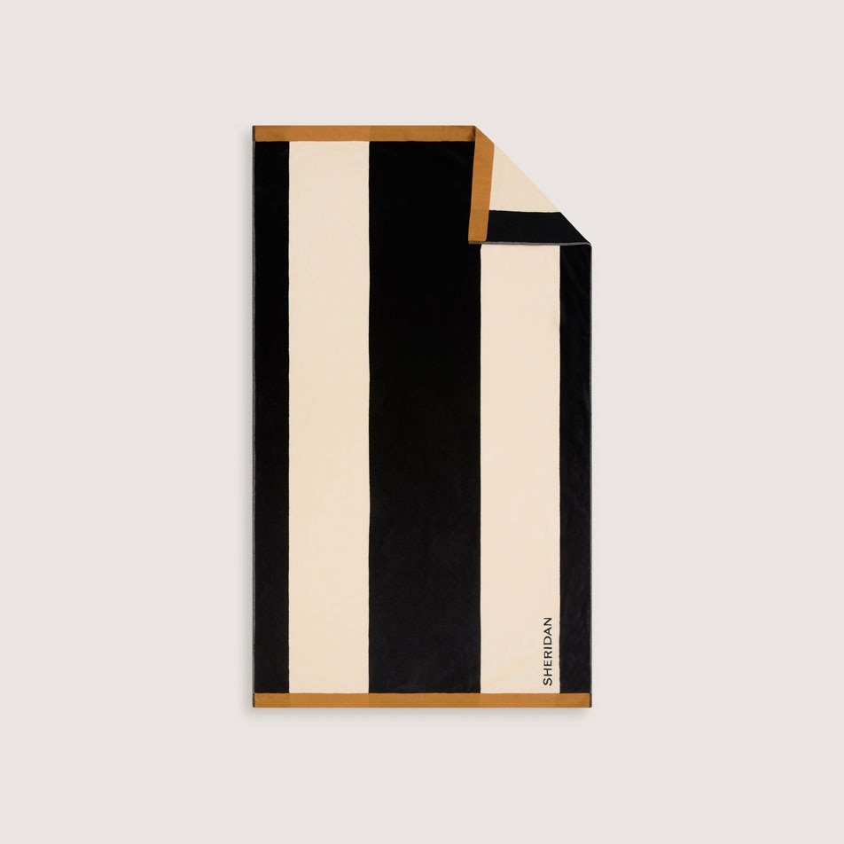 A flay lay image of a black and white bold stripe beach towel