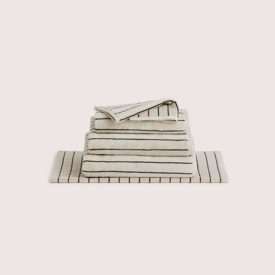 A stack of folded Aven Stripe towels in the colour limestone