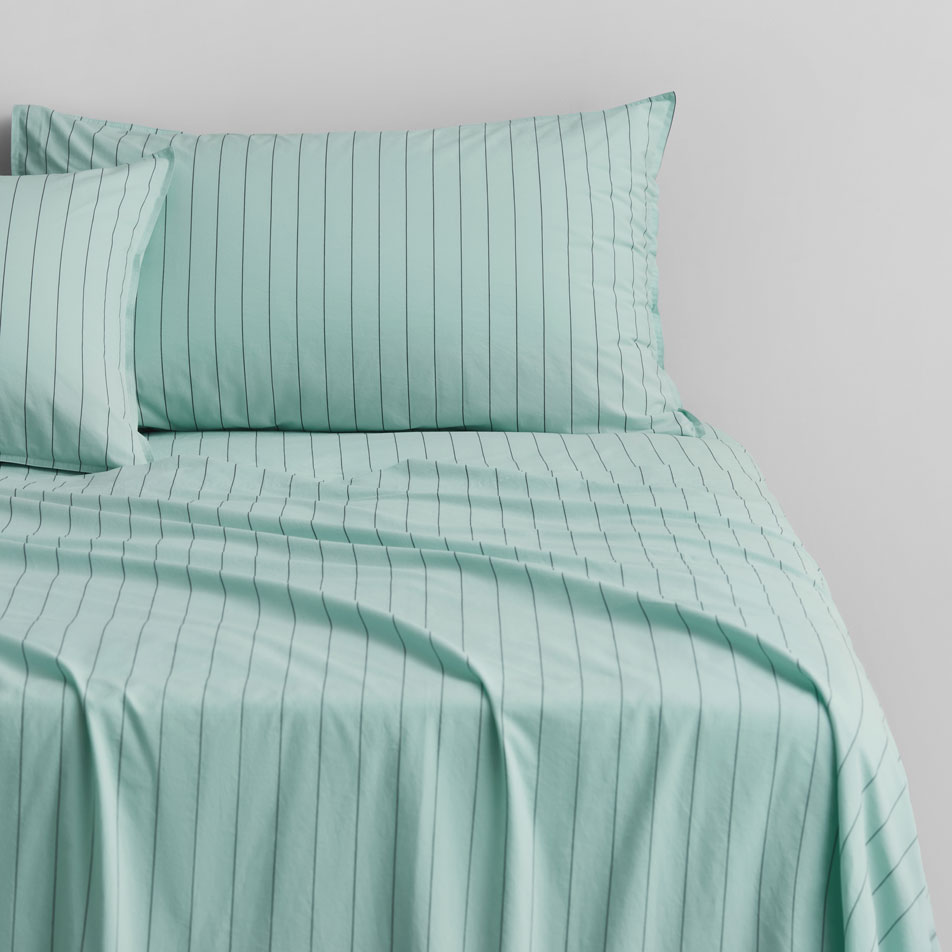 A close-up of a bed with blue stripe sheets and pillowcases.