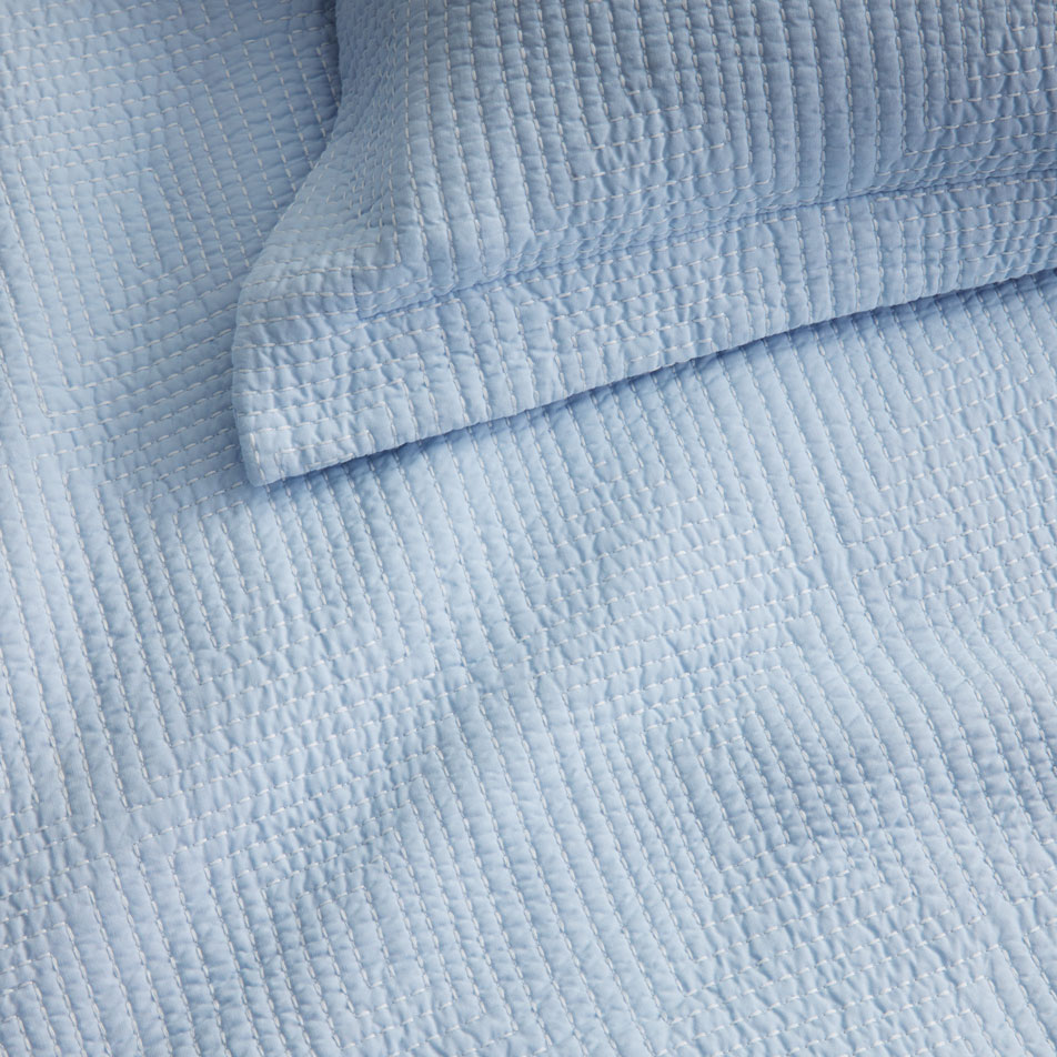 A close-up of blue fabric with textured embroidery.