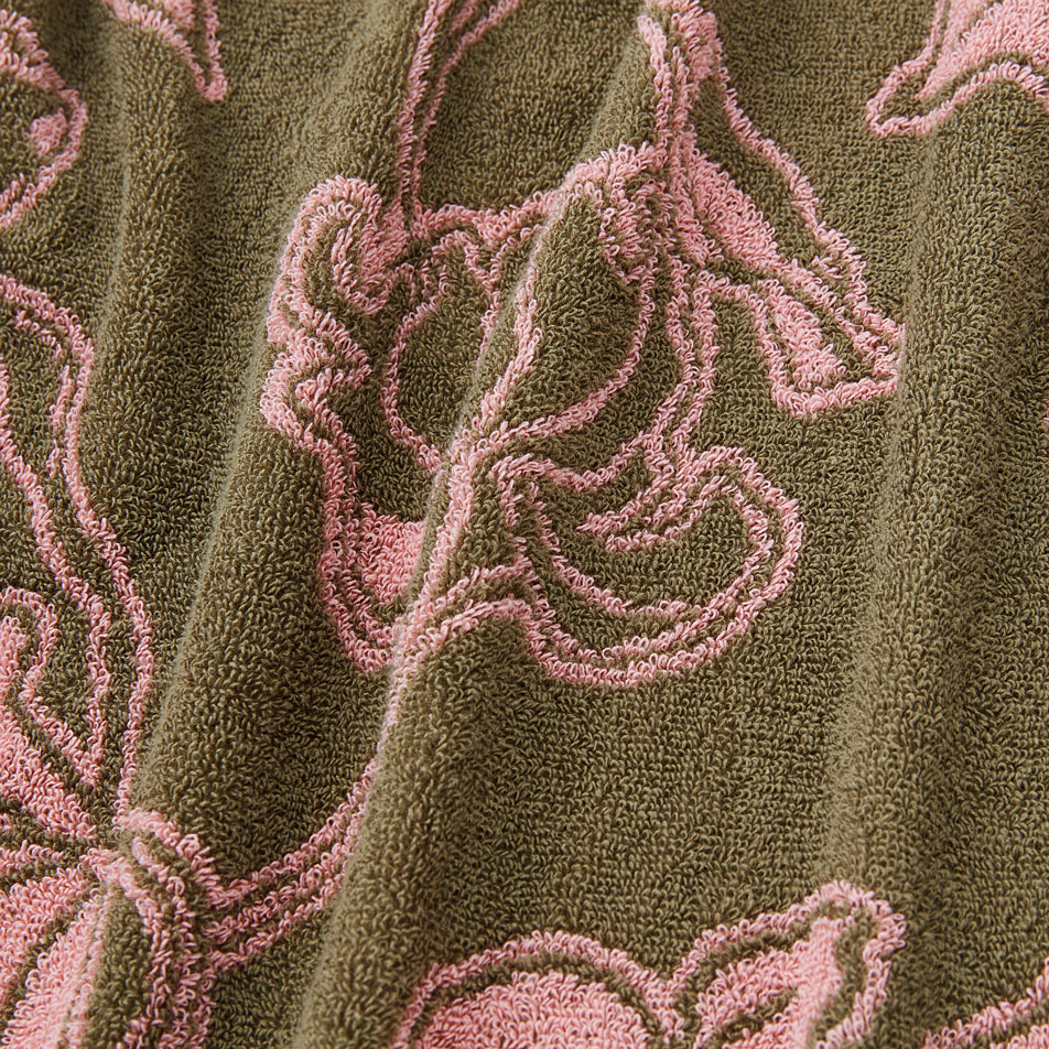 Close-up of green cotton terry fabric with pink floral pattern