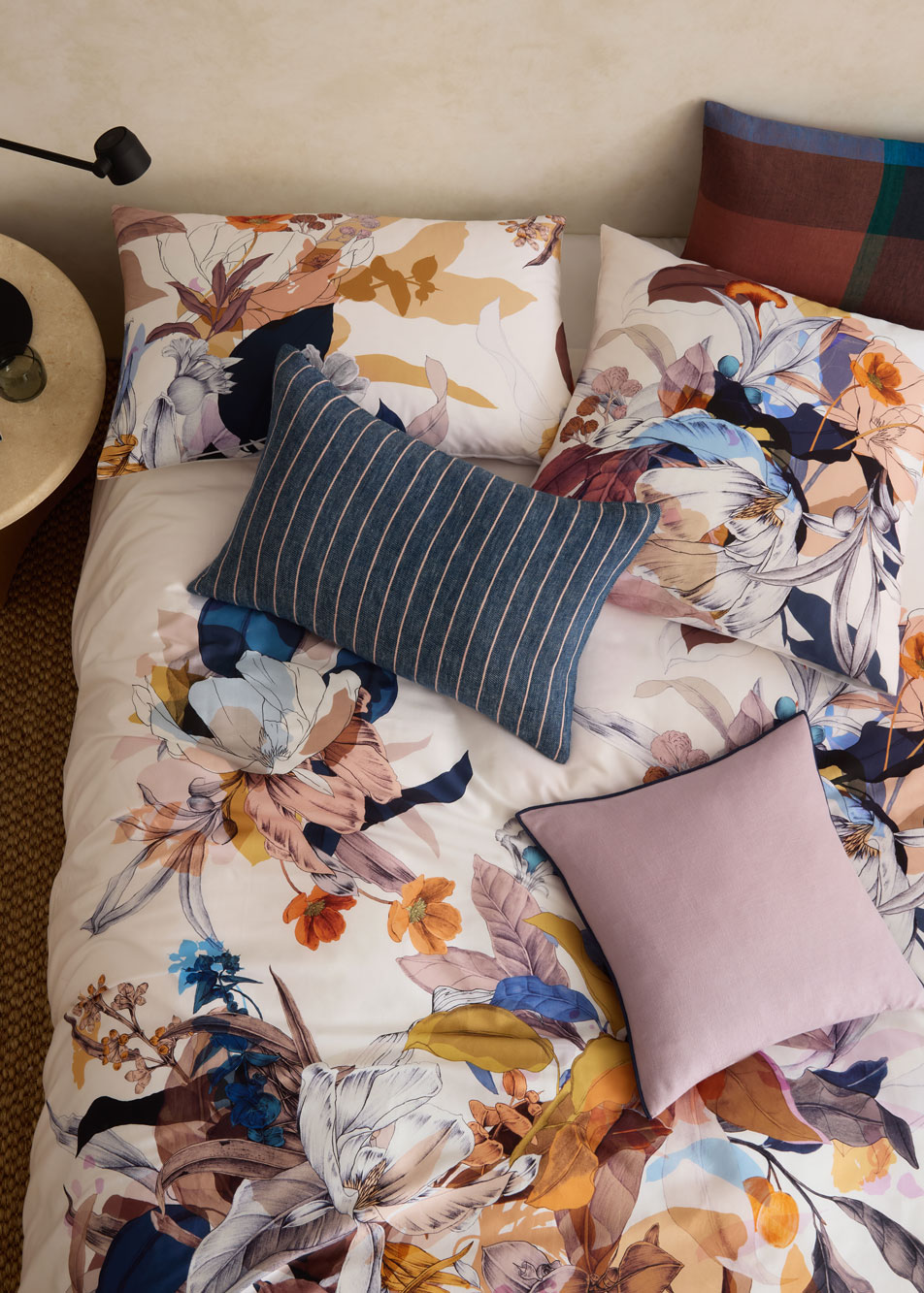 A floral print bed with different styles of cushions