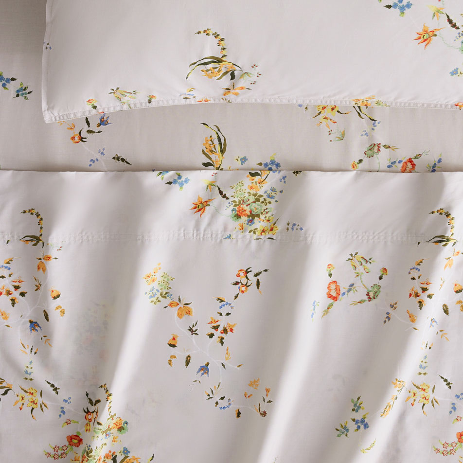 Close up photo of a Calipso ditsy floral sheet set in driftwood. A matching pillow sits on top.