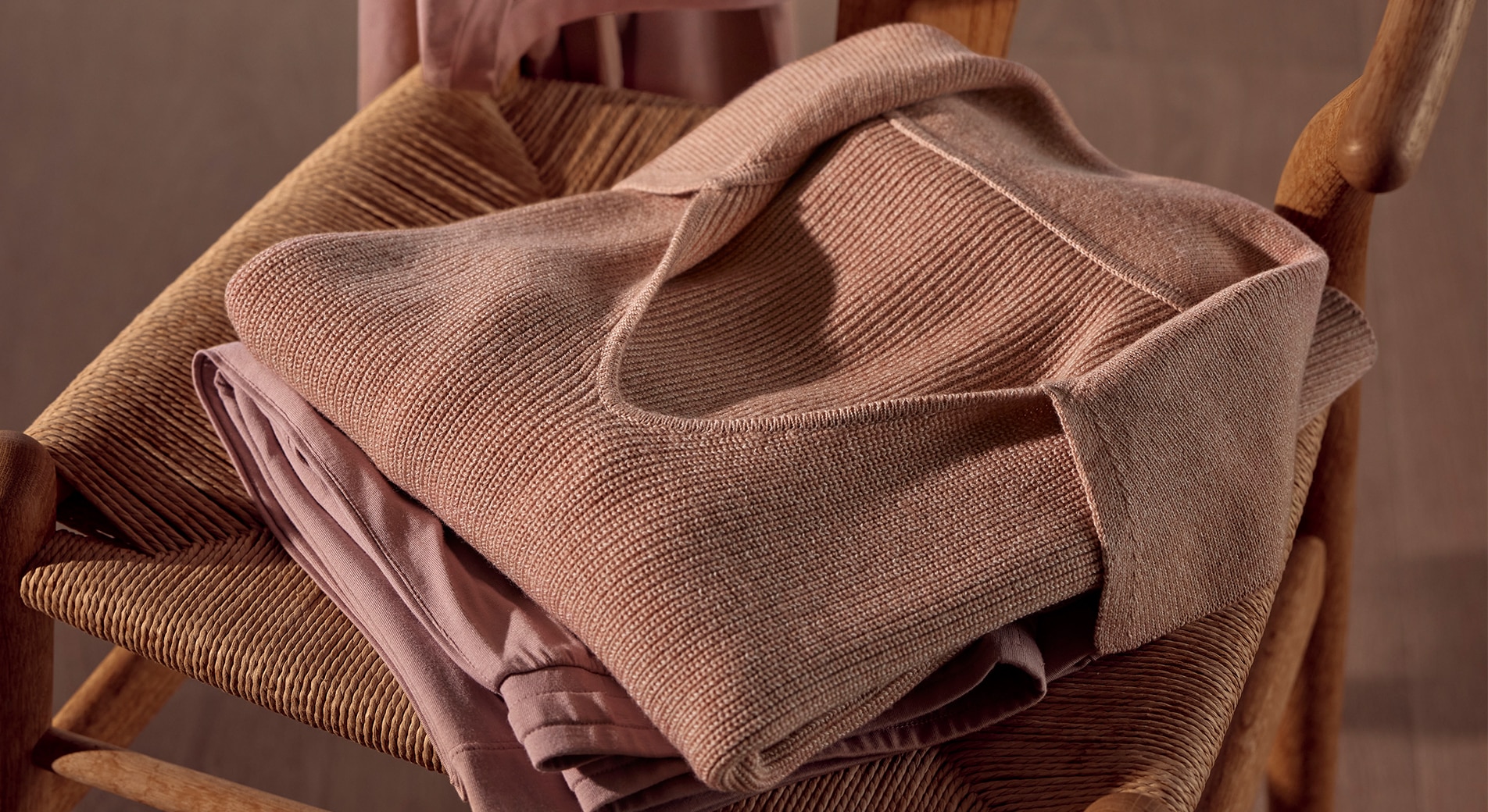 relaxing bedroom ideas. close up of merino knit wool sweater in the colour chia, sitting on a wicker wooden chair.