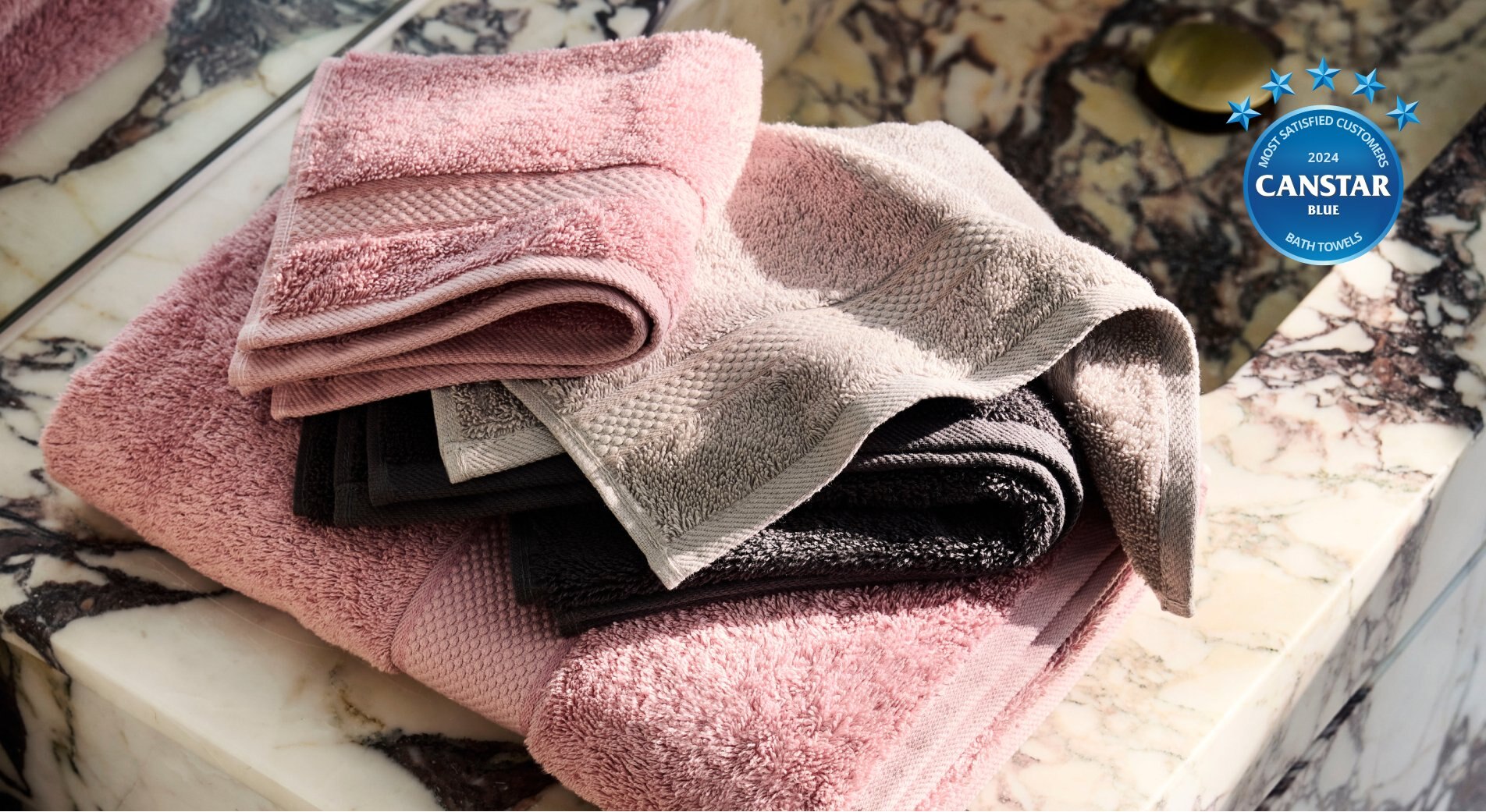 sheridan bath towels in pink and cream draped over white marble counter