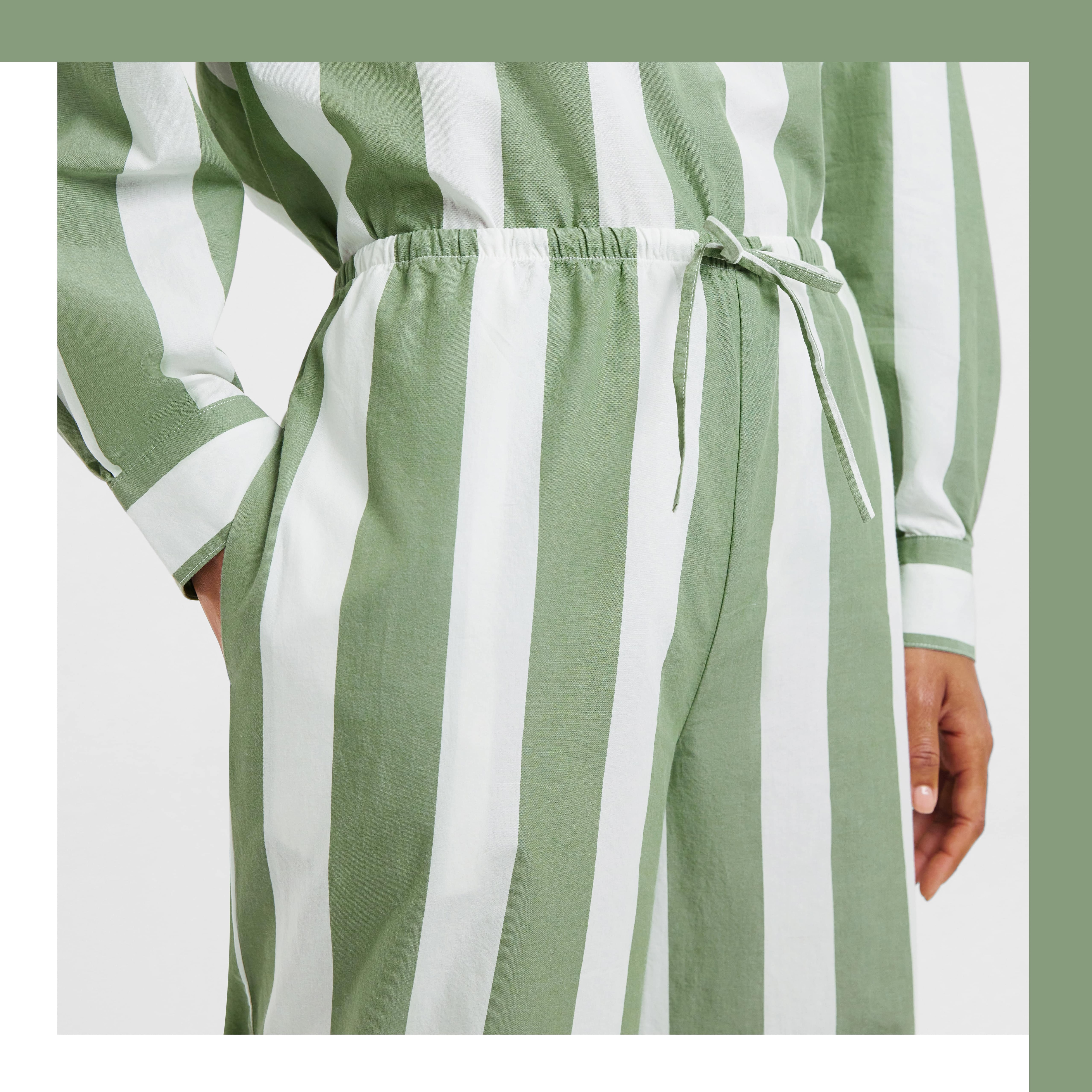 brown skinned woman wears green and white striped cypress pants. one hand is in her pocket, the other hands by her side