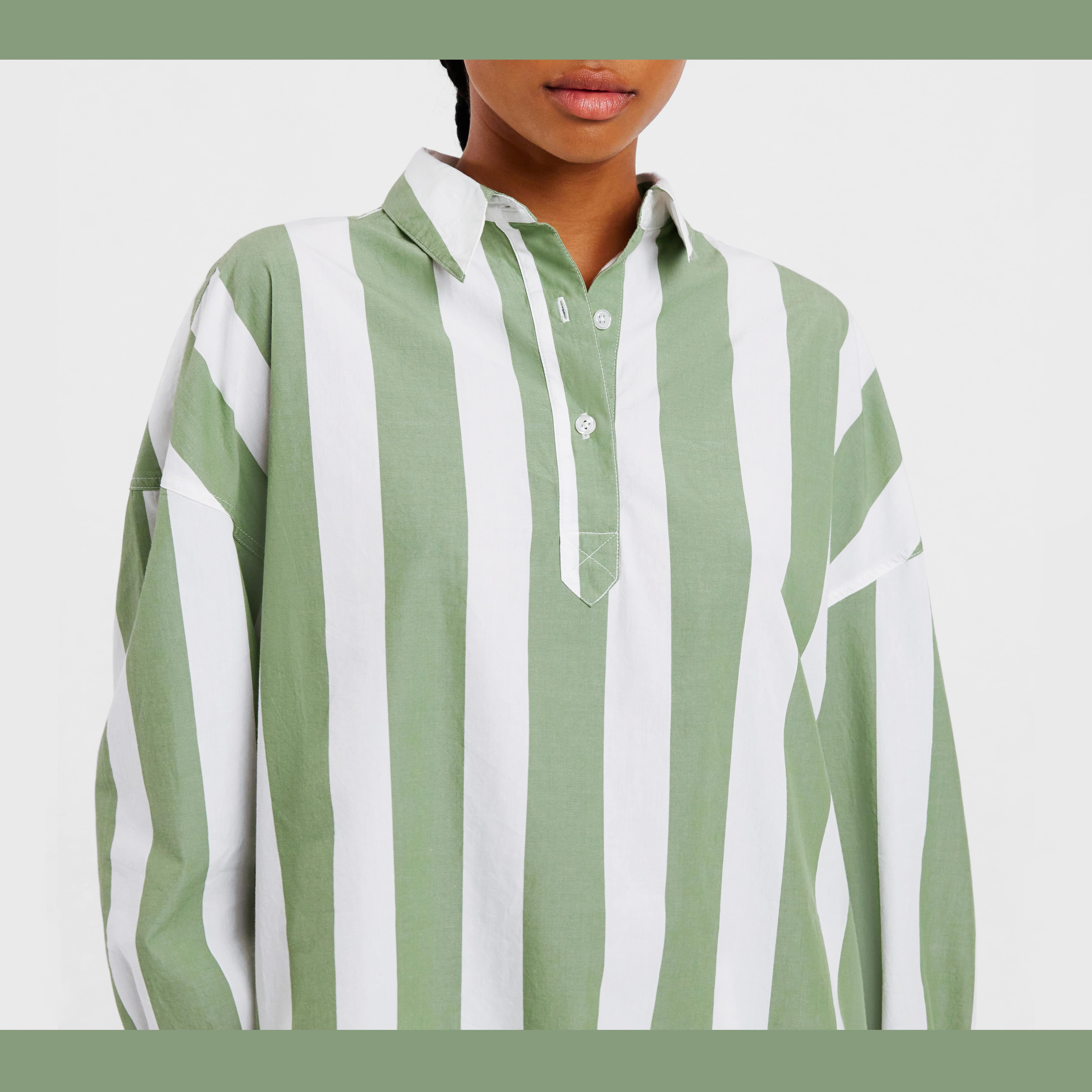 brown skinned woman wears white and green striped cypress shirt. rugby style shirt, relaxed fit with placket and collar.