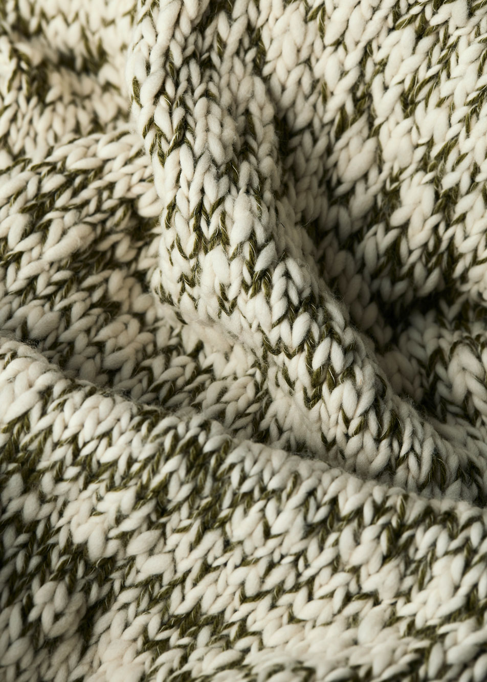 A close-up of a white and green chunky knit throw