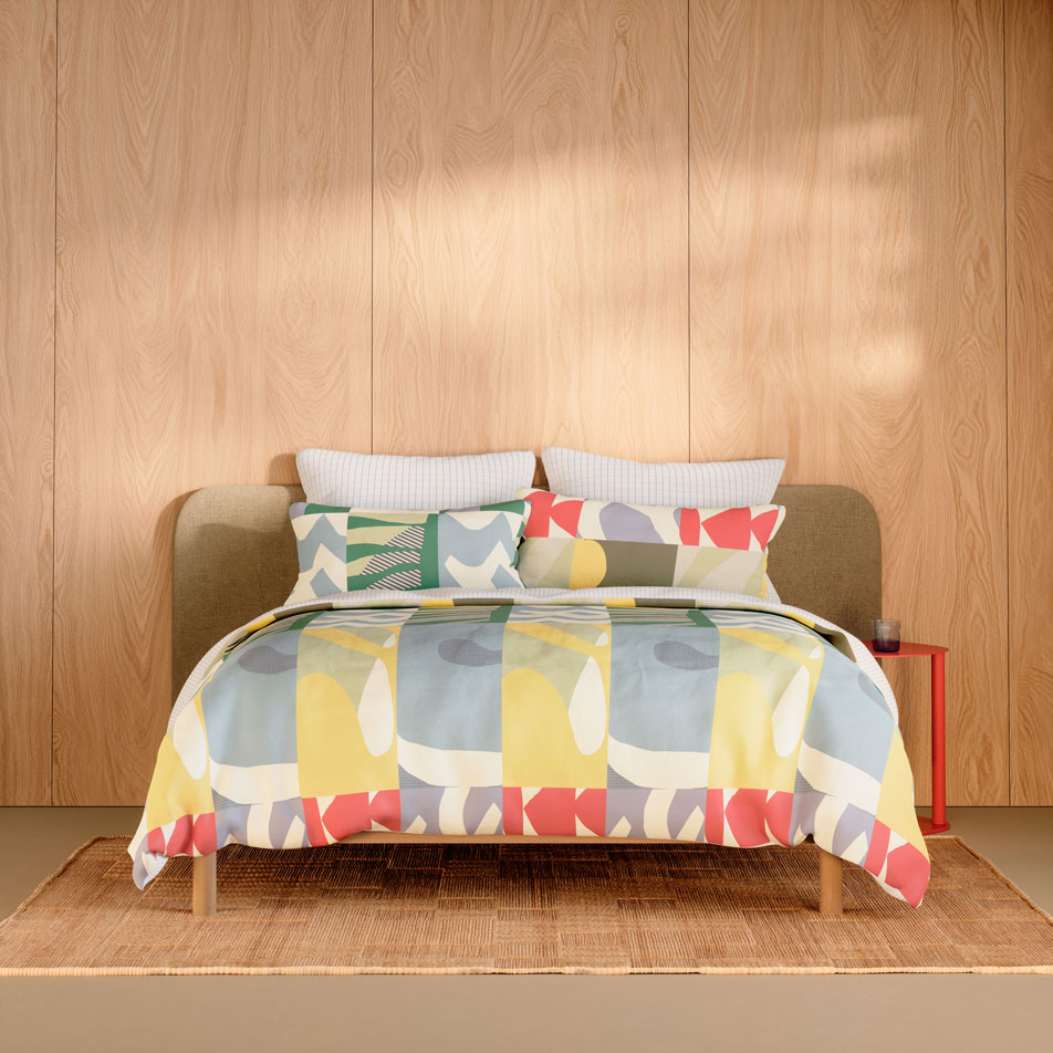 A bed sitting in a minimalist timber room. The bed is showcasing the Falco quilt cover set in the colour multi.