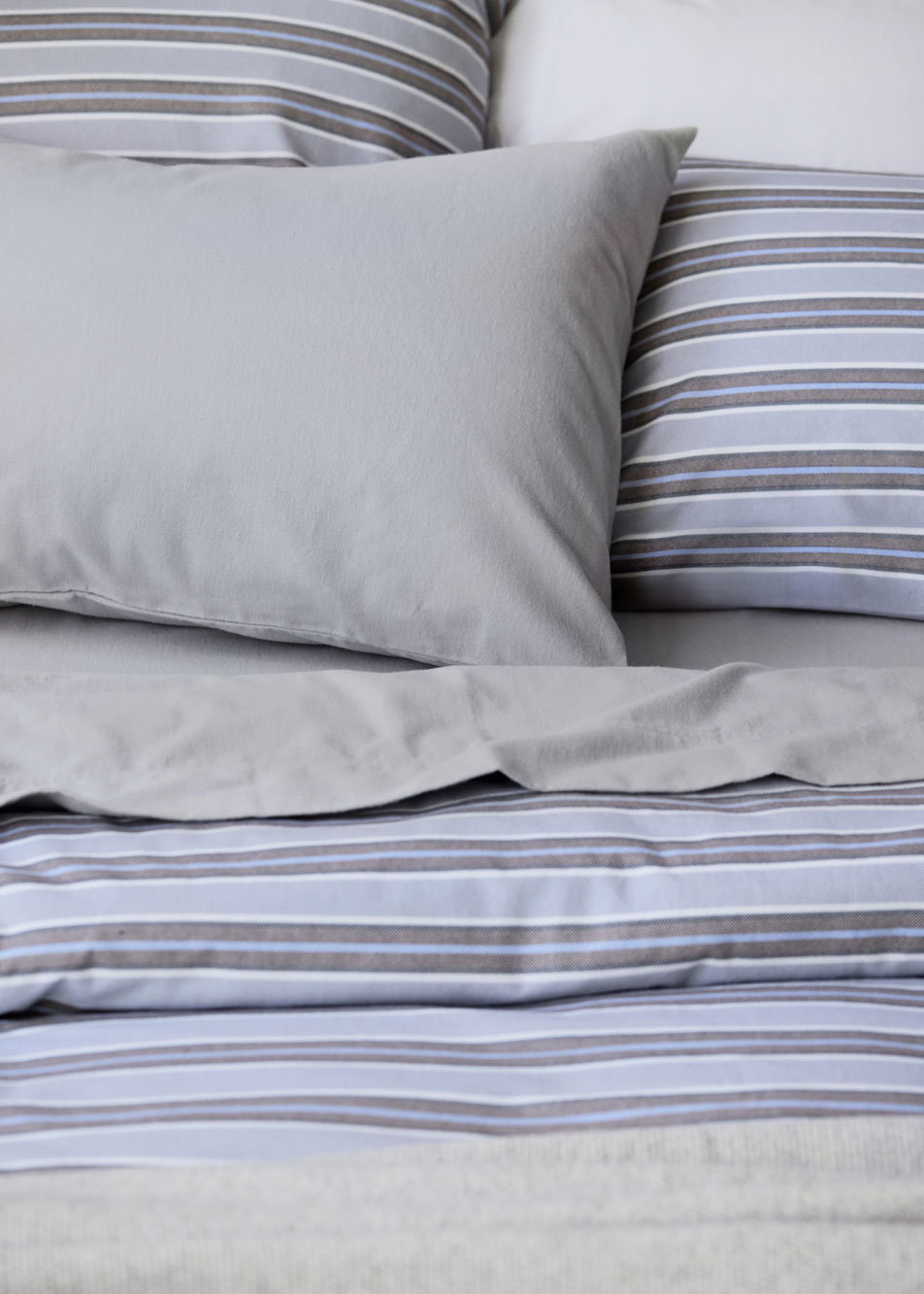 A close-up of a bed dressed in grey and blue stripe flannelette