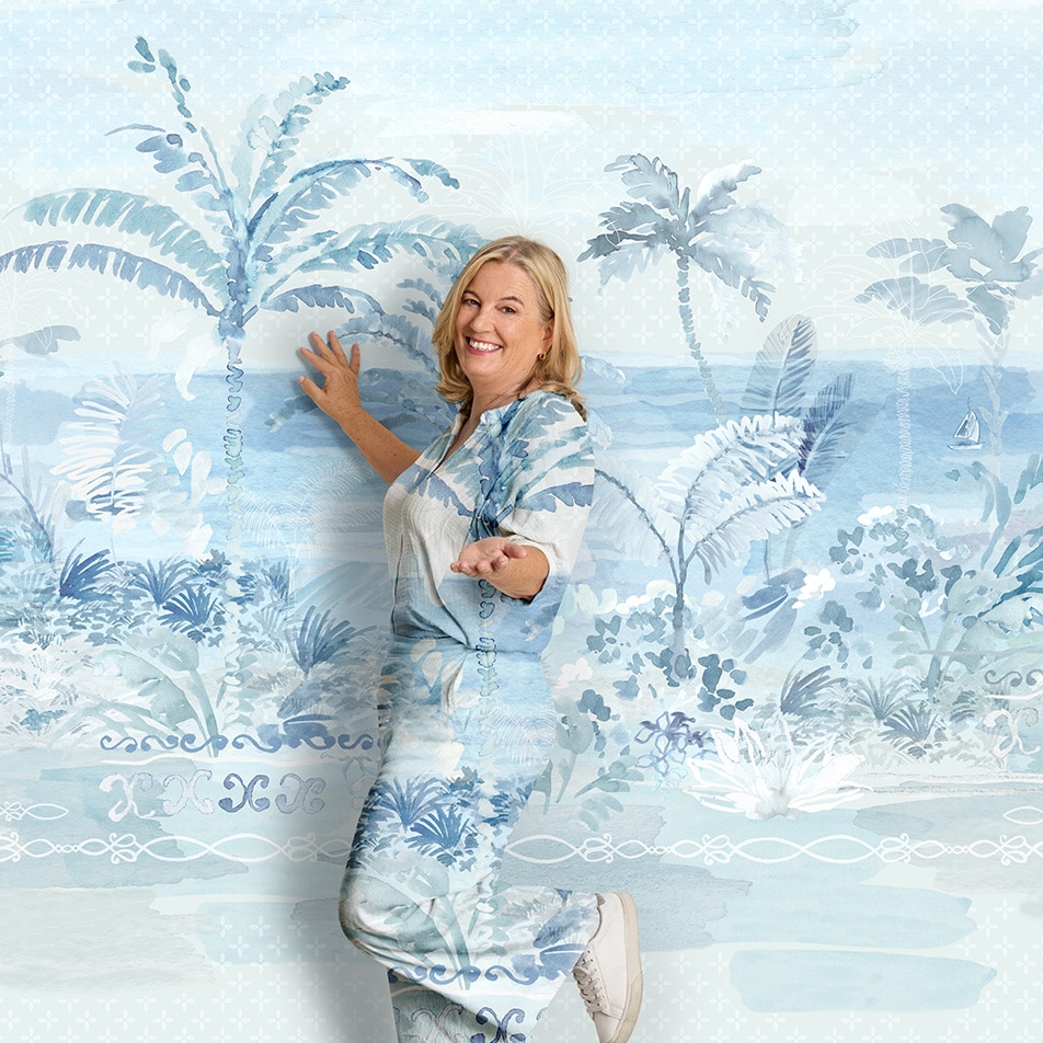 A woman standing in front of a painterly background, playfully pointing to camera. Her clothes are the same print as the backdrop.