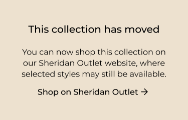 A woman stands, smiling in front of a painterly background. His shirt and pants are in the same matching artwork.