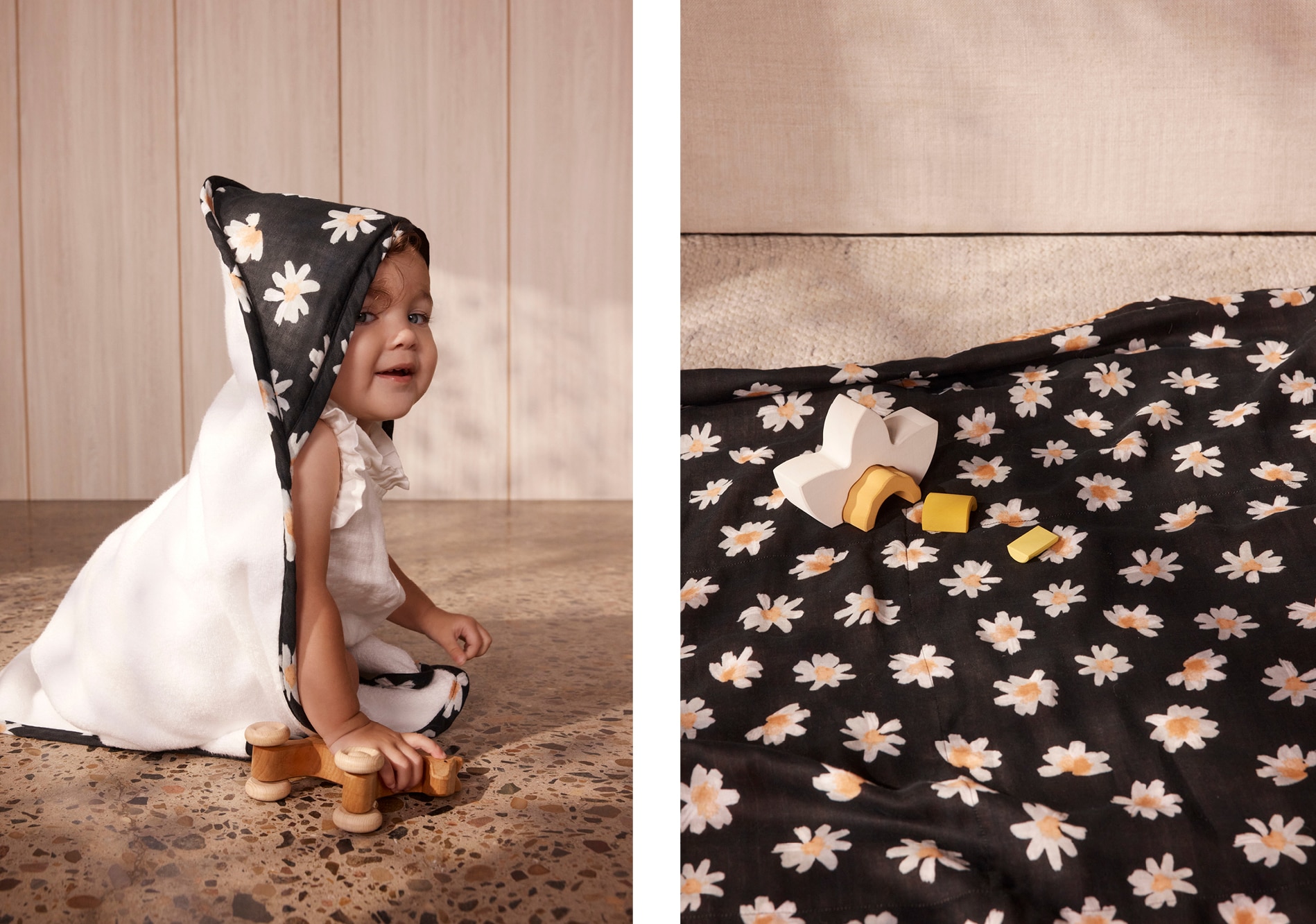 split image. on right, baby holding toy wooden horse, looking at camera, wearing a hooded towel with black and white daisy print. left, the same daisy pattern is on a blanket, spread across the floor. 