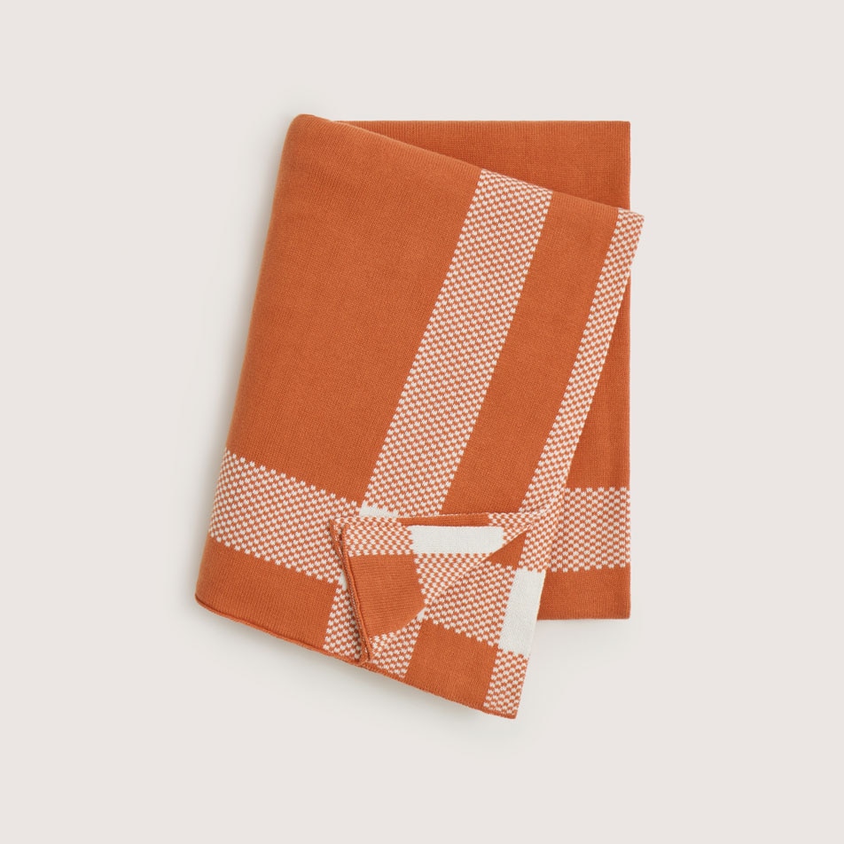 A flat lay image of a Hamill knit throw in burnt orange