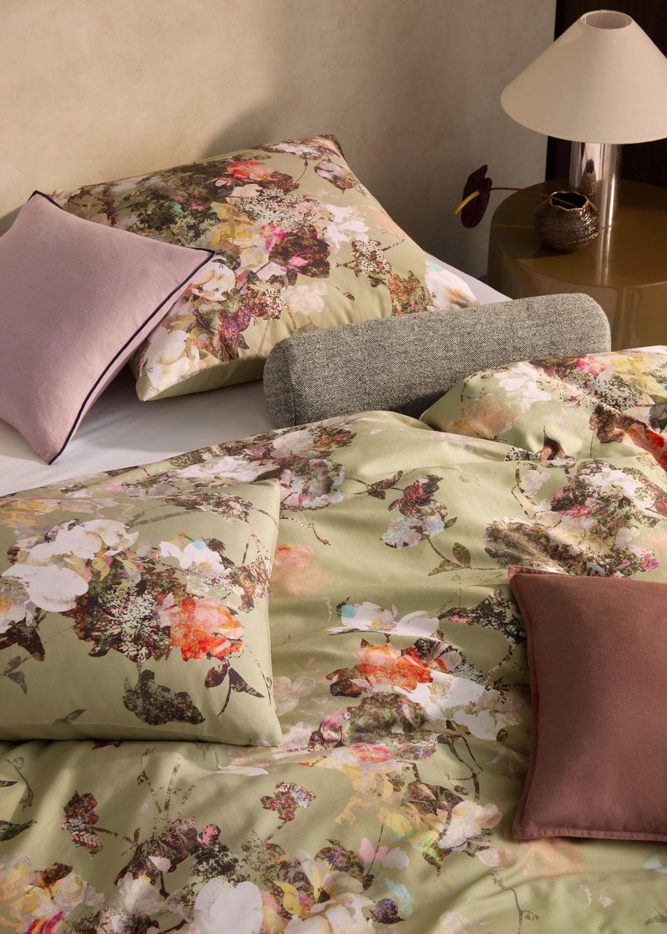 A green floral print bed with different styles of cushions