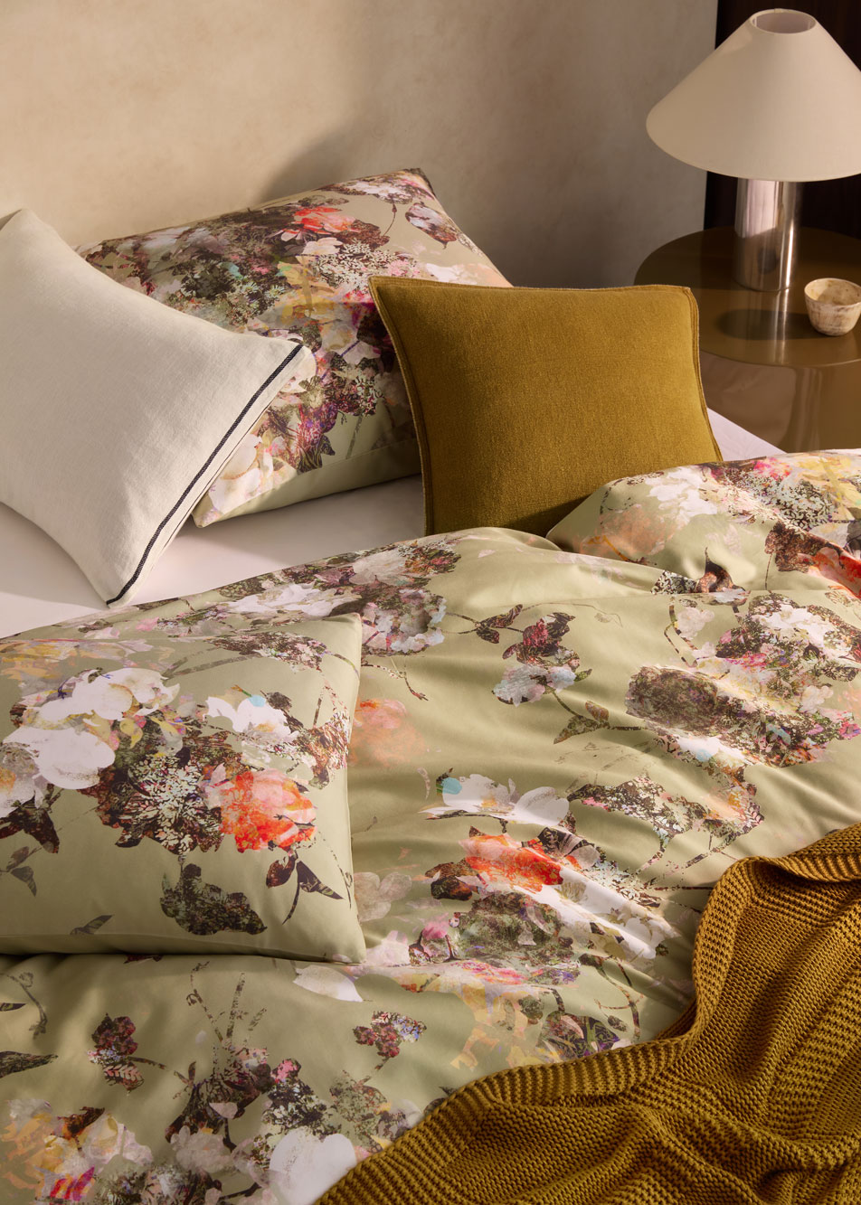 A green floral print bed with different styles of cushions
