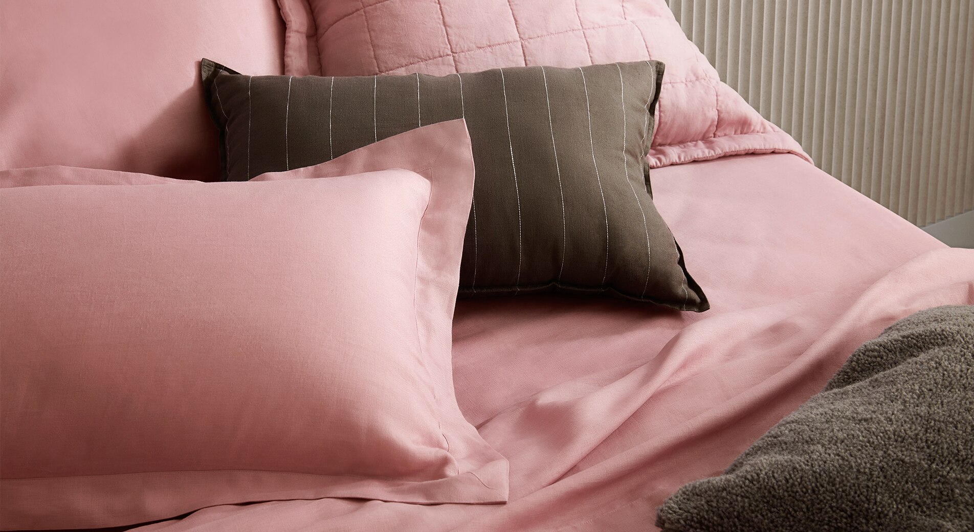 close up shot of pink linen bed with khaki striped linen decorate