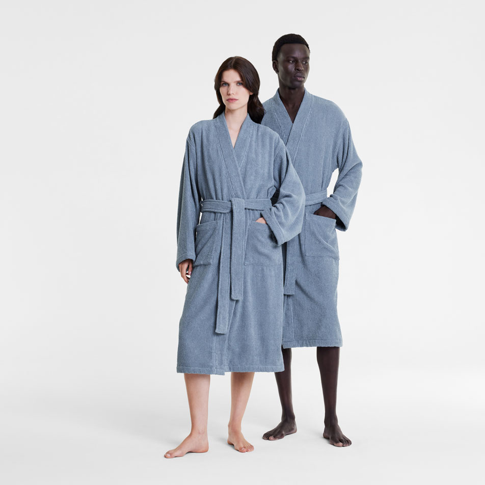 Two models wearing blue Living Textures bathrobes in front of a white background