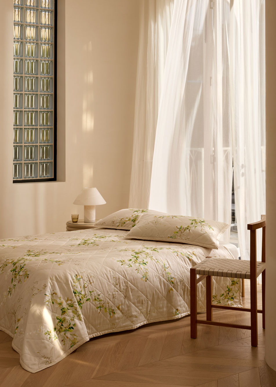 A bed with floral bedding in a modern room with fabric curtains