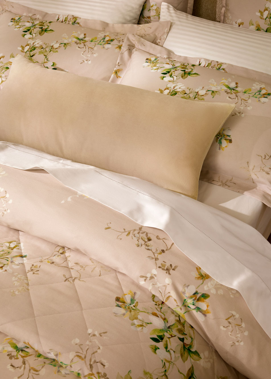A close-up of layers of cushions styled on a bed