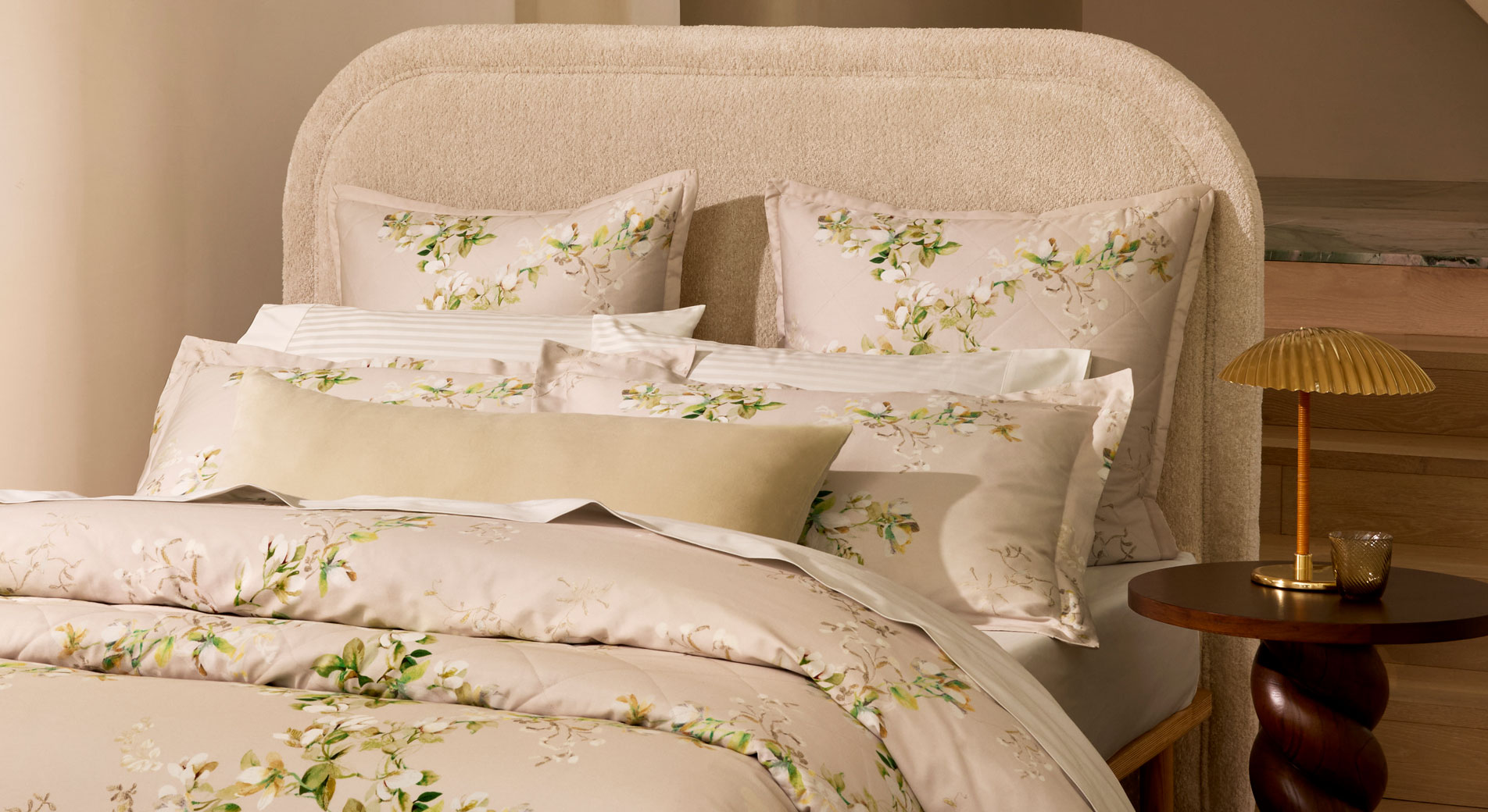 A close-up of a bed with floral sheets and pillowcases