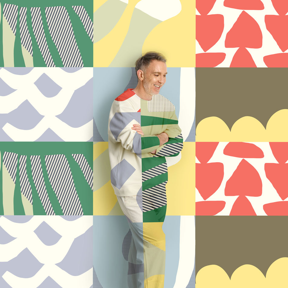A man standing in front of a geometric print background. His clothing is the same print as the backdrop.