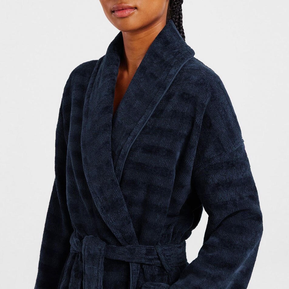 A close up image of a woman modelling a dark blue bathrobe in front of a white background