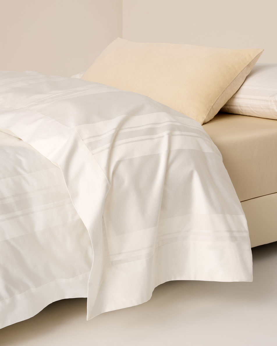 A close-up of a bed dressed in white Millennia sheets