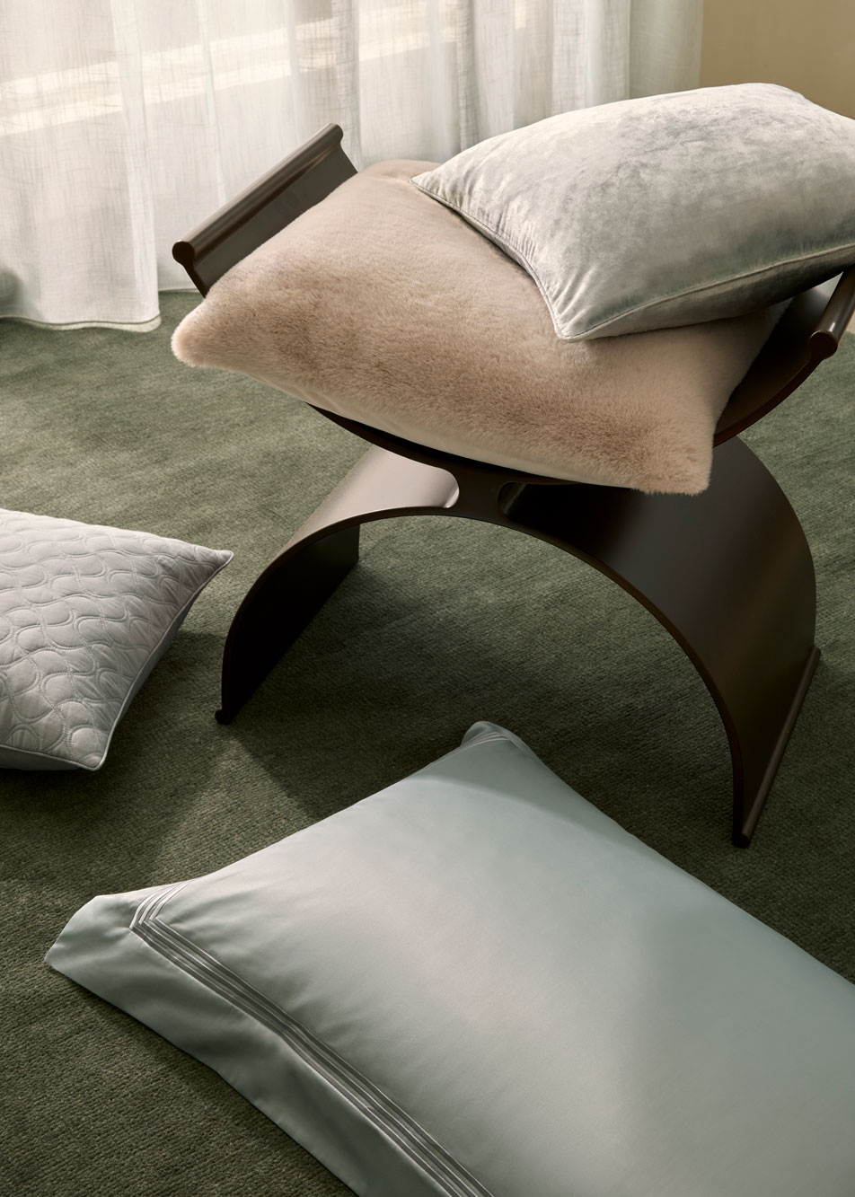 Various cushions scattered on a stool and carpeted floor